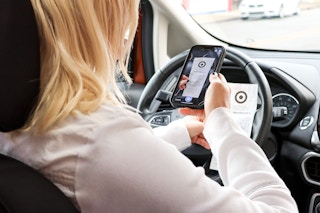 a woman holding up a receipt in her car 