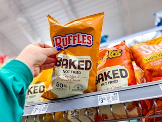 hand grabbing a bag of baked lays chips off walmart shelf