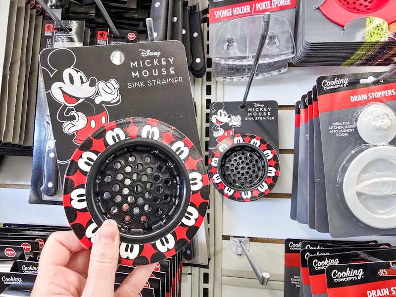 person holding a mickey mouse sink strainer in front of kitchen items