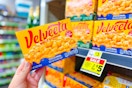 hand holding velveeta shells and cheese in front of dollar general shelf