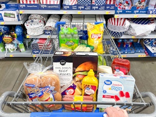 Someone pushing a cart filled with grilling essentials at Walmart