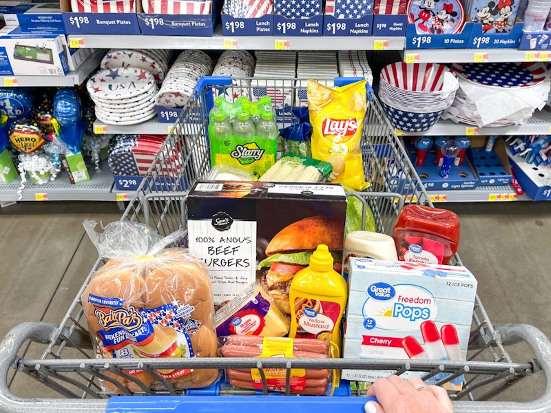 Someone pushing a cart filled with grilling essentials at Walmart