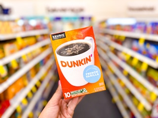 hand holding box of 10 Dunkin coffee K-cup pods in store aisle