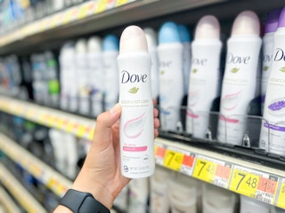 Hand holding Dove Dry Spray Deodorant in front of shelf at Walmart