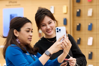 Apple employee and customer looking at an iphone 14 in the apple store