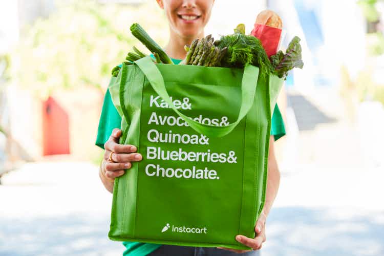 Instacart delivery person holding instacart shopping bag