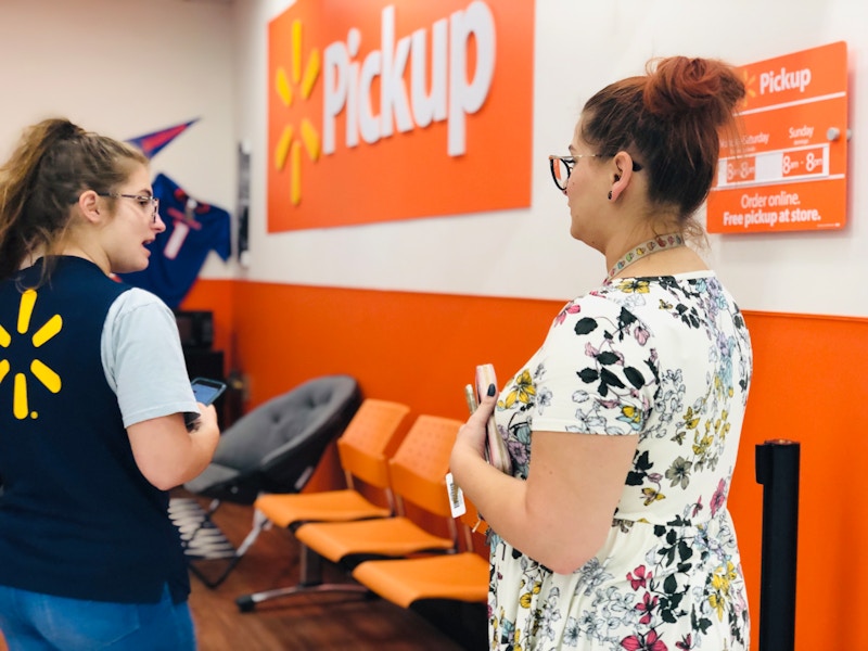 A woman visiting the Walmart pickup location and speaking to a Walmart associate