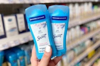 hand holding two sticks of secret ph deodorant in a store aisle