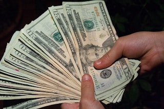 A person holding a bunch of twenty dollar bills.