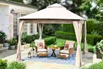 Lifestyle image of a tan soft top gazebo in an outdoor setting