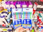 hand holding two 6-packs of Oral-B toothbrushes
