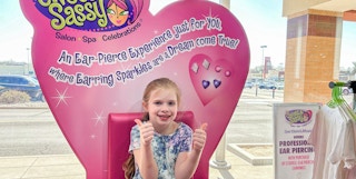 a child sitting in the ear piercing chair at Sweet & Sassy