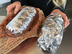 two chipotle burritos on table 