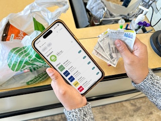 a person holding an iphone with a coupon app in the dollar tree store 