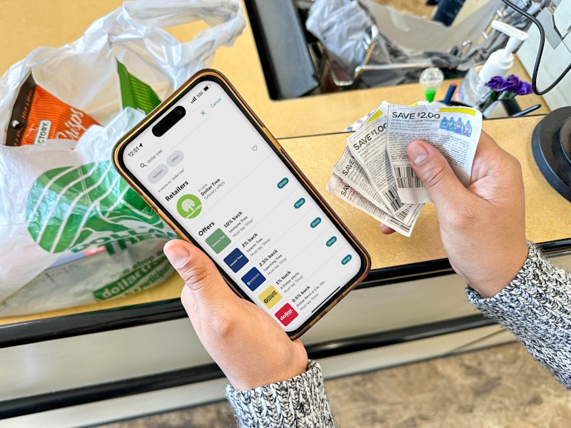 a person holding an iphone with a coupon app in the dollar tree store 