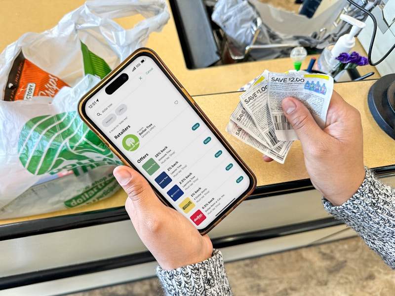a person holding an iphone with a coupon app in the dollar tree store
