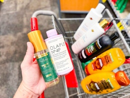hand holding hair care products over a shopping cart