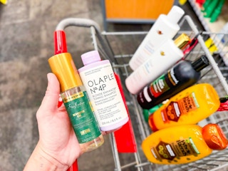 hand holding hair care products over a shopping cart