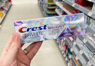 hand holding a tube of crest 3d white brilliance toothpaste at walgreens