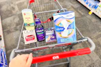 person pushing a cart with old spice deodorant, olay moisturizer, zzzquil products, and always pads
