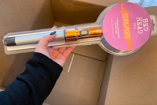 hand holding bed head tigi curlipops curling iron wand over a box