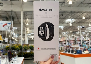A hand holding up an Apple Watch SE.