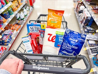 person pushing a cart with toilet paper, floss, toothpaste, nutri-grain bars, and more