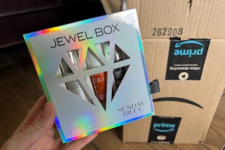 hand holding sunday riley jewel box kit with amazon box behind it