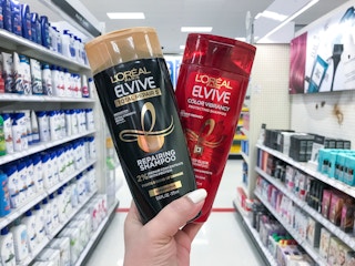 hand holding 2 bottles of l'oreal paris elvive shampoo in an aisle at target
