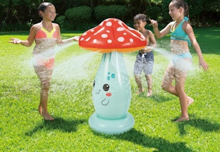 kids playing and running around an inflatable mushroom sprinkler in the grass