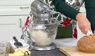 a person using a silver kitchen mixer on a counter