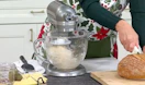 a person using a silver kitchen mixer on a counter