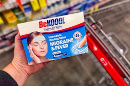 person holding a package of be koool migraine relief patches over a cart