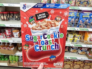 person holding a box of cereal in front of shelves