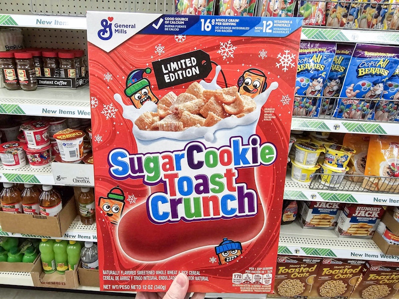 person holding a box of cereal in front of shelves