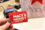 hand holding Macy's Money card at checkout with bag