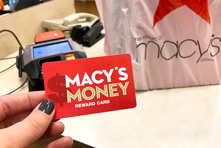 hand holding Macy's Money card at checkout with bag