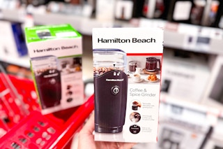 hand holding a hamilton beach coffee grinder in front of a target shelf