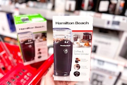 hand holding a hamilton beach coffee grinder in front of a target shelf