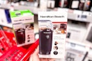 hand holding a hamilton beach coffee grinder in front of a target cart
