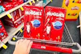 person pushing a cart with huggies diapers in it