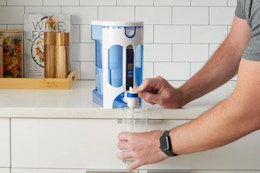 person getting water out of a filtration system on the countertop