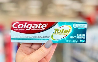 hand holding box of Colgate Total toothpaste