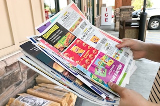 someone looking at newspaper coupon inserts