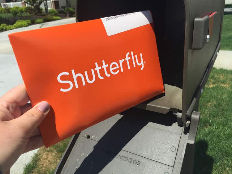 A person's hand taking a Shutterfly envelope from a mailbox.