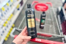 person holding a bottle of tresemme shampoo over a cvs cart