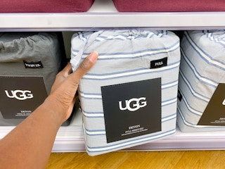 someone pulling an ugg sheet set off a bottom shelf in bed bath and beyond