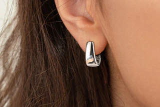 An ear with a sterling silver .925 huggie hoop in it. The earring is about 13 x 16 millimeters