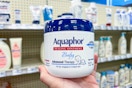person holding a tub of aquaphor baby ointment