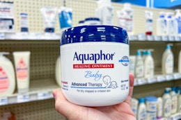 person holding a tub of aquaphor baby ointment
